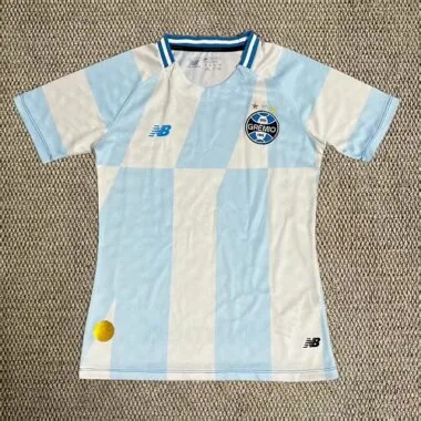 Capa do álbum Camisa feminina do Grêmio para jogos fora de casa da época 2026/27